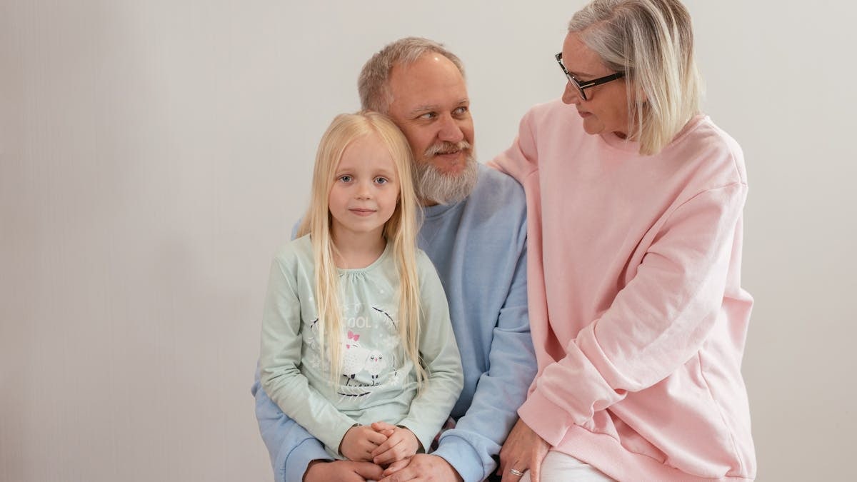 Grandparents lovingly embrace their granddaughter in a bright, studio setting, capturing family warmth and connection.